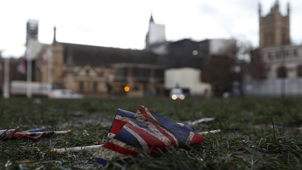 A British Union flag from Brexit day celebrations lies in the grass in front of the Palace of Westminster in London, early Saturday, Feb. 1, 2020.