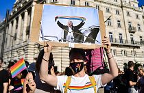 A demonstrator holds a placard showing Hungarian Prime Minister Viktor Orban holding a scarf in rainbow colours