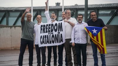 Catalan leaders hold a banner and Catalan pro-independence flag outside Lledoners prison in Sant Joan de Vilatorrada, near Barcelona