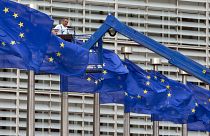 أعلام الاتحاد الأوروبي ومن خلفها مقر المفوضية الأوروبية في بروكسل
