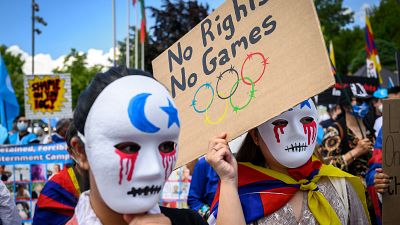 Tibetan and Uyghur activists hold placards and wear masks during a protest against Beijing 2022 Winter