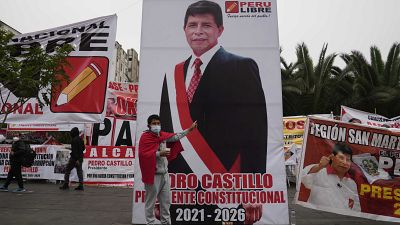 Un joven posa junto a un cartel gigante del candidato izquierdista Pedro Castillo en Lima, Perú.