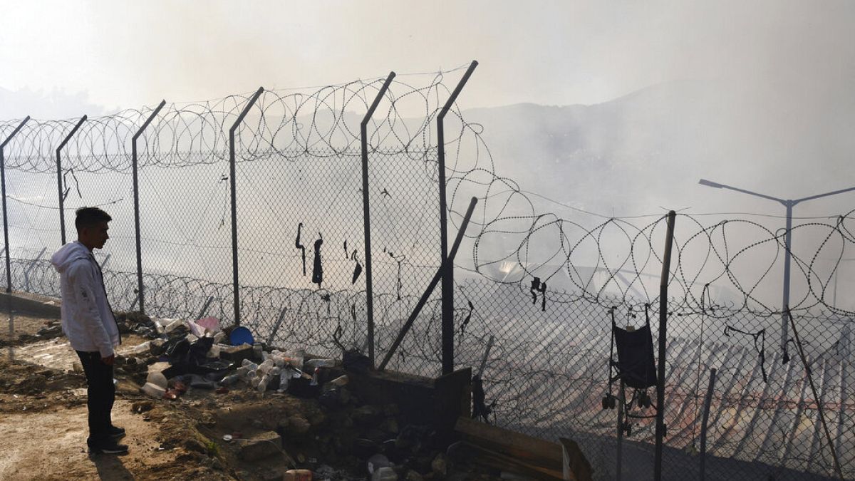 FILE - In this file photo dated Wednesday, Nov. 11, 2020, a migrant stands outside a refugee camp after a fire on the eastern Aegean island of Samos, Greece. 