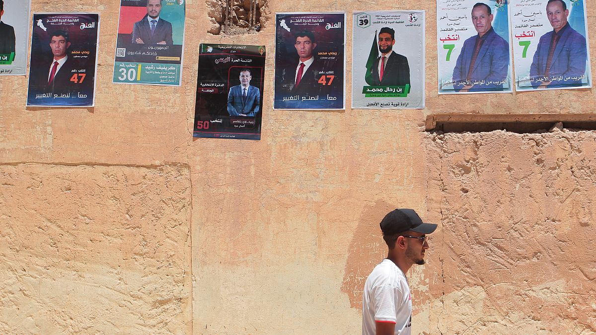 رجل يمشي قرب معلقات انتخابية في عين وسارة (ولاية الجلفة) البعيدة عن العاصمة الجزائرية بنحو 190 كلم. 2021/06/10
