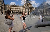 Two girls take pictures outside the Louvre Museum courtyard, in Paris, June 9, 2021 as France reopened its borders to foreign travellers.