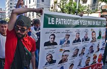جزائريون يحملون لافتات عليها صور لنشطاء محتجزين في السجن، خلال مظاهرة مناهضة للحكومة في العاصمة الجزائر، 7 مايو 2021