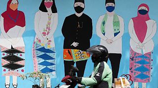 دراجة نارية أمام لوحة جدارية للتوعية حول فيروس كورونا في جاكرتا، إندونيسيا.