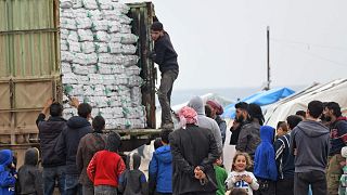نازحون سوريون يصطفون لتلقي مساعدات إنسانية في مخيم في بلدة المحمدية، بالقرب من بلدة دير البلوط على طول الحدود مع تركيا، 21 شباط 2020