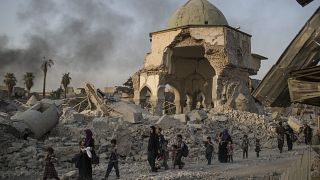 Fleeing Iraqi civilians walk past the damaged al-Nuri mosque as Iraqi forces continue their advance against IS militants in the Old City of Mosul, Iraq, July 4, 2017.