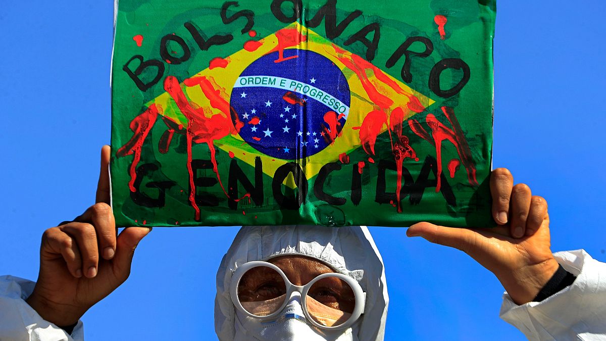 متظاهر يرفع صورة علم البرازيل مخضبا بالدم تعبيا عن احتجاج البرازيليين ضد سياسة بولسونارو الخاصة بمكافحة كوفيدـ19. 2021/05/26