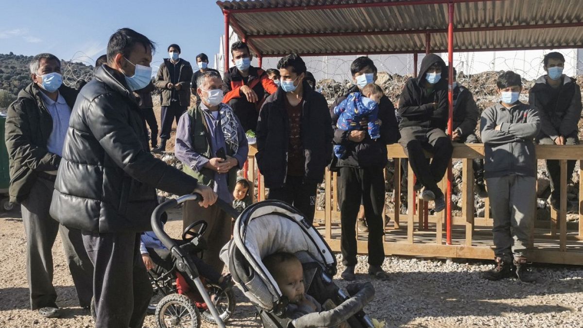 Um grupo de migrantes, com máscaras de proteção, reúne-se do lado de fora do novo campo de refugiados de Kara Tepe, na ilha de Lesbos, em 19 de dezembro de 2020