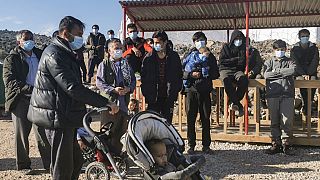 A group of migrants, wearing protective facemasks, gather outside in the new refugee camp of Kara Tepe, in the island of Lesbos, on December 19, 2020.