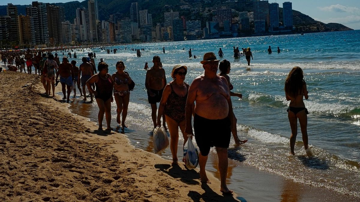 La gente camina por la playa en un día de verano en Benidorm, sureste de España, el viernes 25 de junio de 2021. 