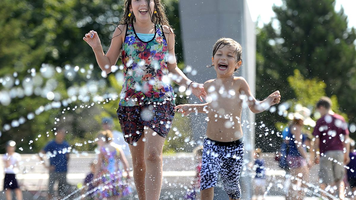 طفلان كنديان يلهوان بالمياه في أحد متنزهات مدينة أوتاوا بعد أن سجلت درجات الحرارة ارتفاعات قياسية في كندا.