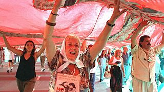 An unidentified Mother of the Disappeared helps carry a giant poster during a demonstration near the military school in Buenos Aires