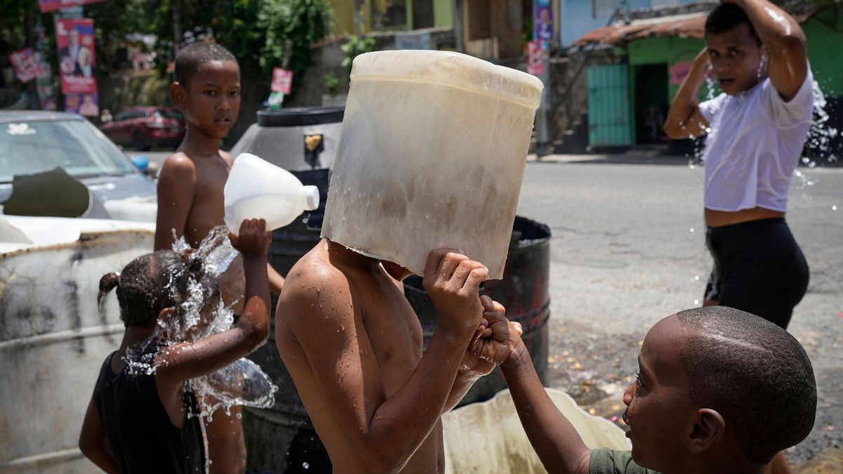  A child covers his head with a bucket on a hot day in the Los Guandules neighborhood of Santo Domingo, Dominican Republic.