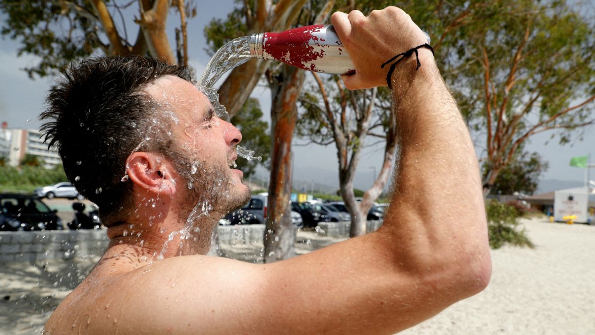 A beach-goer pours water on his face to refresh himself on the Ricanto beach in Ajaccio, on the French island of Corsica as Europe is hit by a major heatwave.