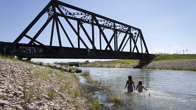 Youngsters cool off in an irrigation canal as a heatwave rages in the United States and Canada
