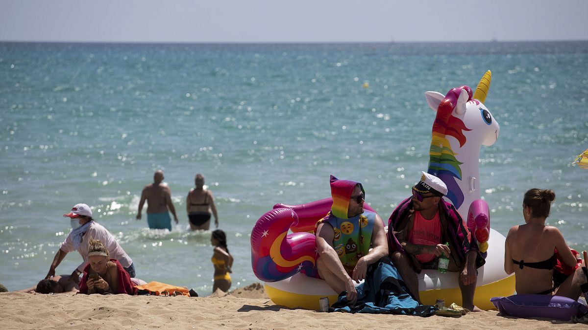 سائحون يستمتعون بالشمس على الشاطئ في جزيرة البليار الإسبانية في مايوركا، إسبانيا.