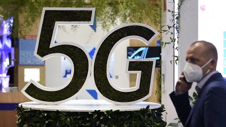 A man uses his phone next to a 5G logo at the Mobile World Congress (MWC) fair in Barcelon