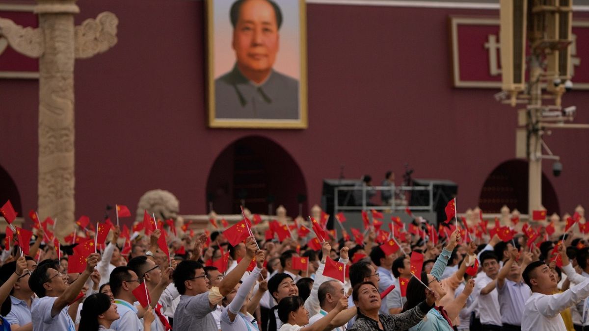 صينيون يلوح بالأعلام وصورة كبيرة لماو تسي تونغ خلال حفل بمناسبة الذكرى المئوية لتأسيس الحزب الشيوعي الصيني في بكين.