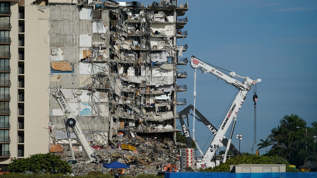 Workers peer up at the rubble pile at the partially collapsed Champlain Towers South condo building, on Thursday, July 1, 2021, in Surfside, Florida.