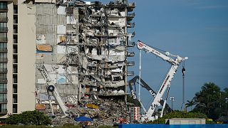 Workers peer up at the rubble pile at the partially collapsed Champlain Towers South condo building, on Thursday, July 1, 2021, in Surfside, Florida.