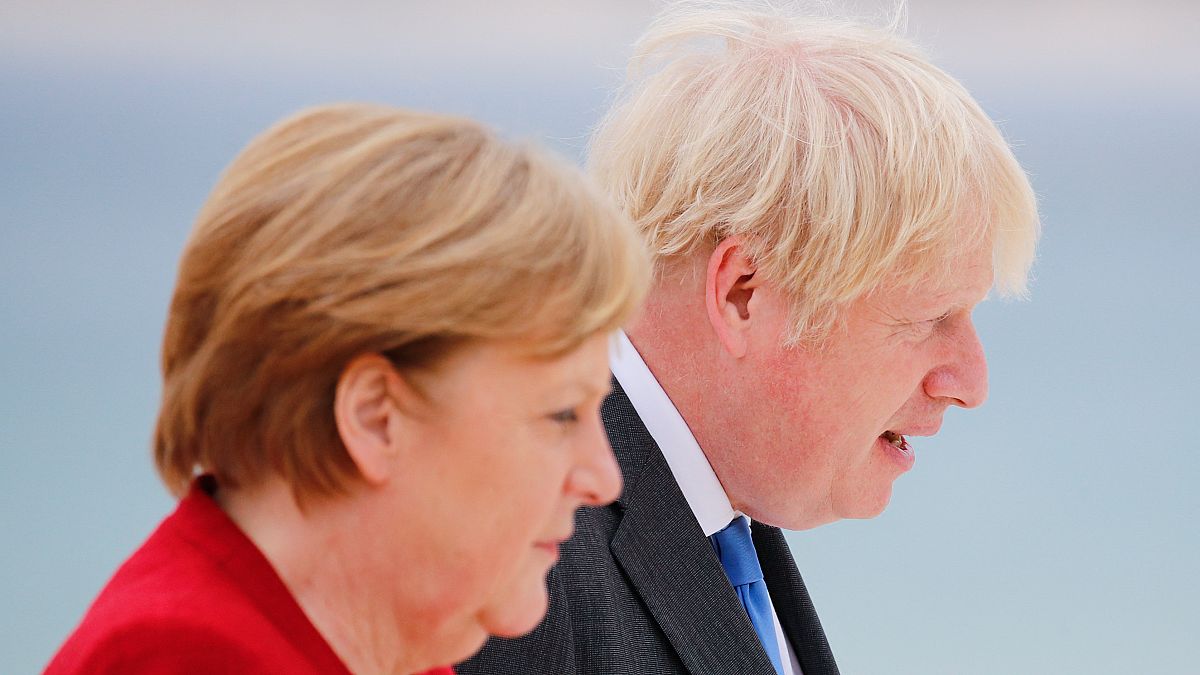Britain's Prime Minister Boris Johnson and German Chancellor Angela Merkel (L) look on as they arrive for the G7 summit in Carbis Bay, Cornwall, on June 11, 2021.