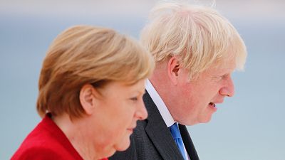 Britain's Prime Minister Boris Johnson and German Chancellor Angela Merkel (L) look on as they arrive for the G7 summit in Carbis Bay, Cornwall, on June 11, 2021. Britain's Prime Minister Boris Johnson and German Chancellor Angela Merkel (L) look on as they arrive for the G7 summit in Carbis Bay, Cornwall, on June 11, 2021.