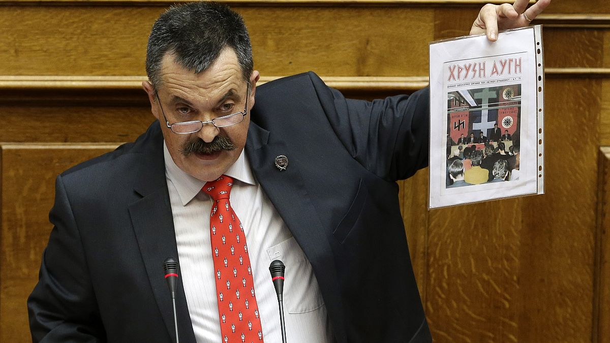 Golden Dawn's Christos Pappas shows a copy of his party magazine as he speaks to lawmakers during his time as a member of the Greek parliament, Athens, June 4, 2014.