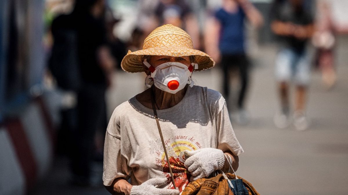 A woman wearing a face mask, walks down a street on June 21, 2021. 