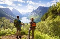 Two hikers admire the view of a valley in Norway.
