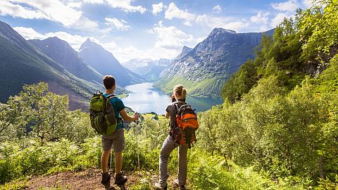 Two hikers admire the view of a valley in Norway.