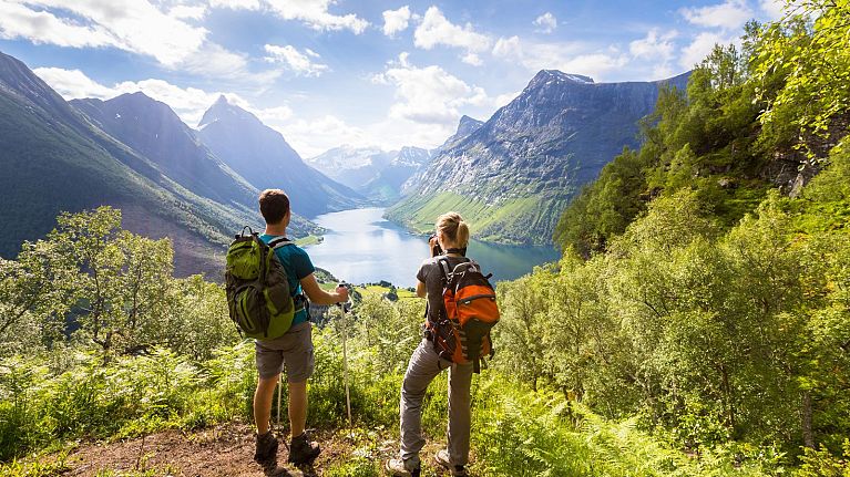 Two hikers admire the view of a valley in Norway.