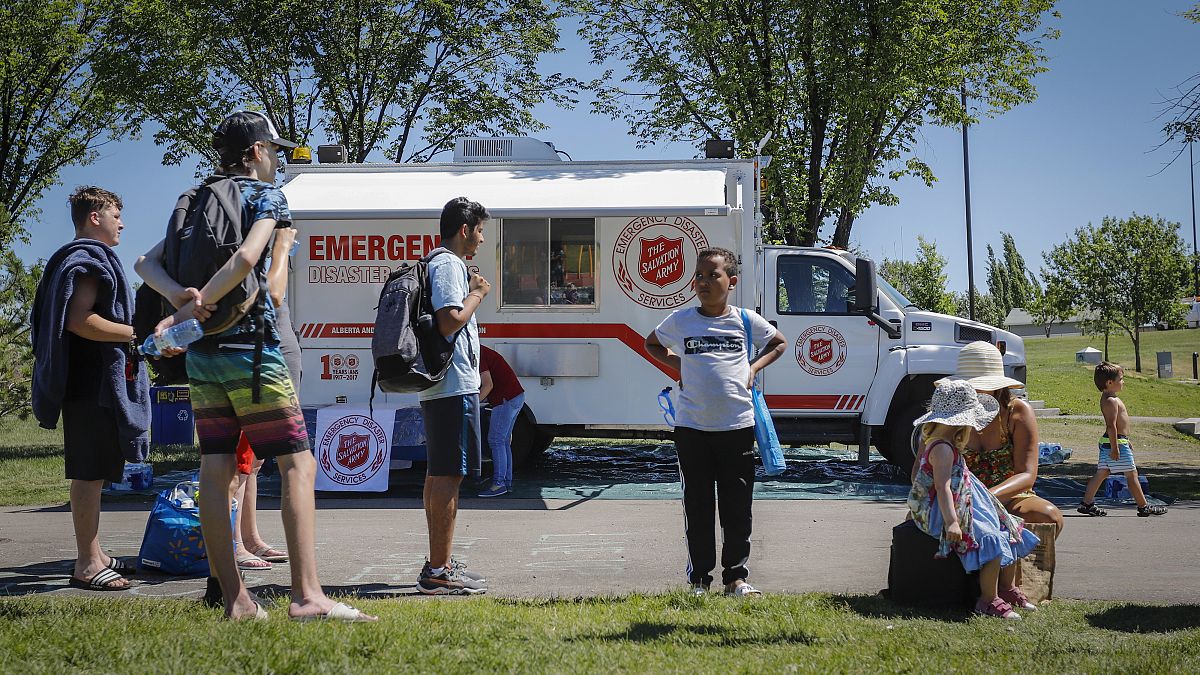 A Salvation Army EMS vehicle is setup as a cooling station as people lineup to get into a splash park while trying to beat the heat in Calgary, Alberta.