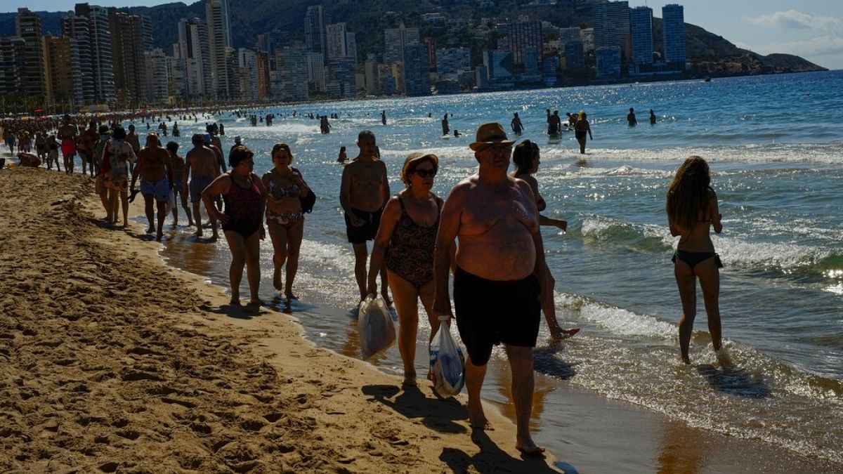  In this June 25, 2021, file photo, people walk along the beach on a summer's day in Benidorm, southeast Spain. 