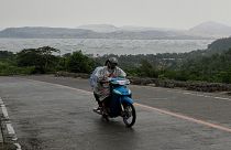 رجلان على دراجة نارية يغادران المنطقة القريب من بركان تال في مقاطعة باتانجاس بالفلبين حيث  تم إجلاء آلاف