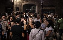 Un grupo de jóvenes está de fiesta nocturna en una concurrida calle de Barcelona.