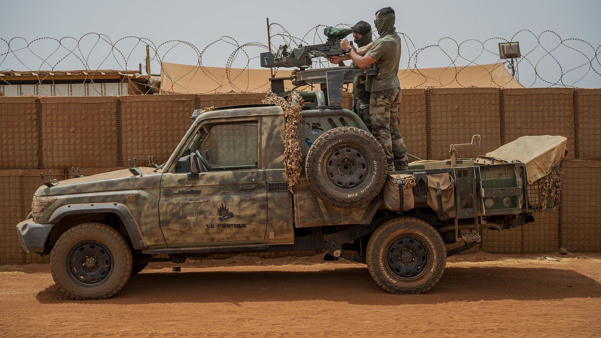 French Barkhane force commandos mount a machine gun on a camouflaged pickup as Malian workers drive by before heading on a mission from their base in Gao, Mali, June 7, 2021. 
