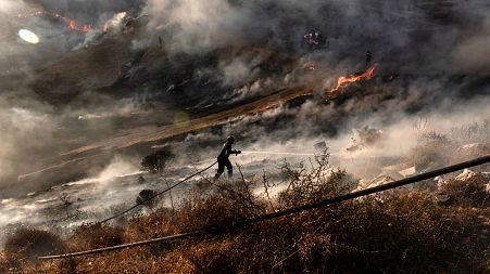 A firefighter douses the flames in an effort to contain a fire near the Kotsiatis area, on the outskirts of Cyprus' capital Nicosia.