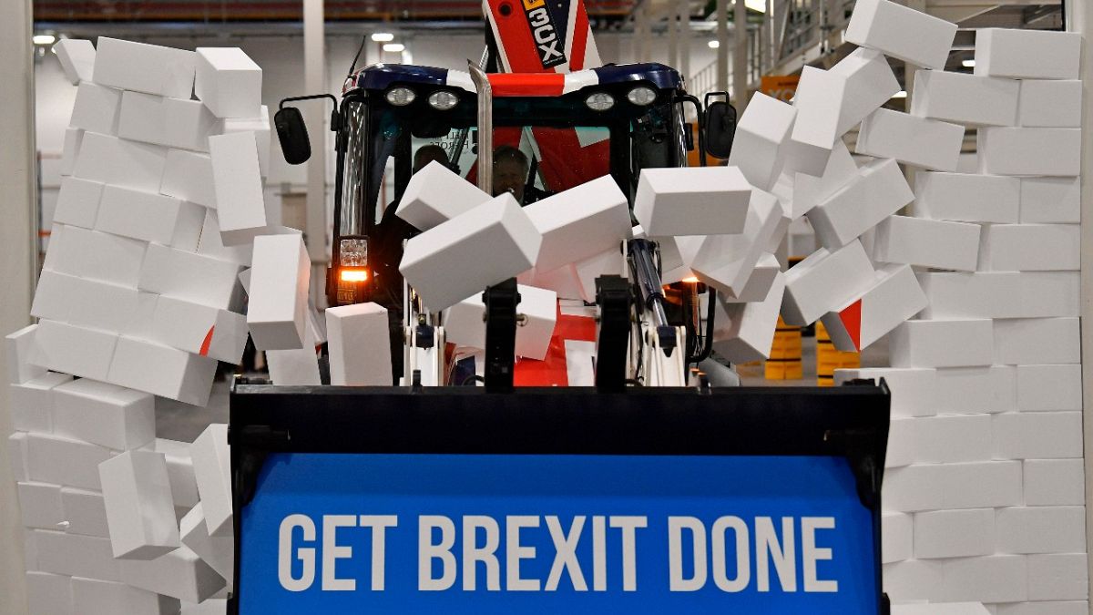 UK Prime Minister Boris Johnson drives a JCB through a symbolic wall during an election campaign event at a JCB plant, Uttoxeter, England, December 10, 2019. 