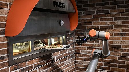 This photograph taken on July 1, 2021, shows "Pazzi", a pizza-making robot at work in a restaurant in Paris.