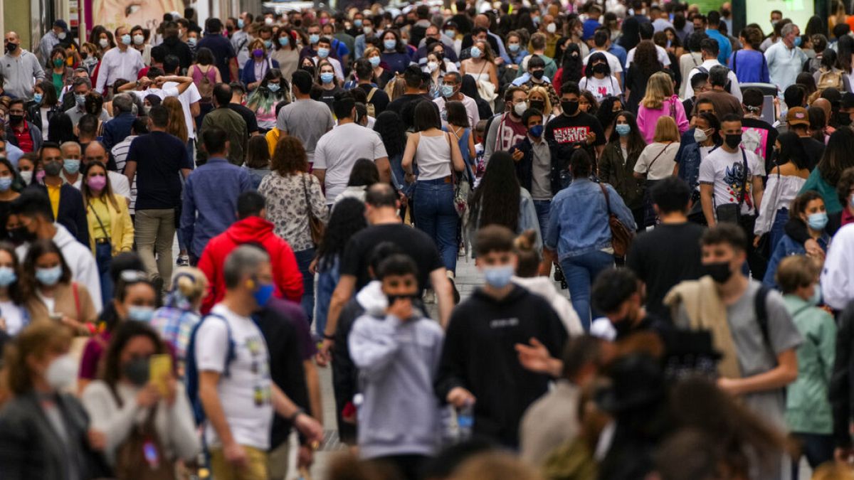 FILE: In this June 5, 2021, file photo, people wearing face masks to protect against the spread of coronavirus, walk along a commercial street in downtown Madrid, Spain