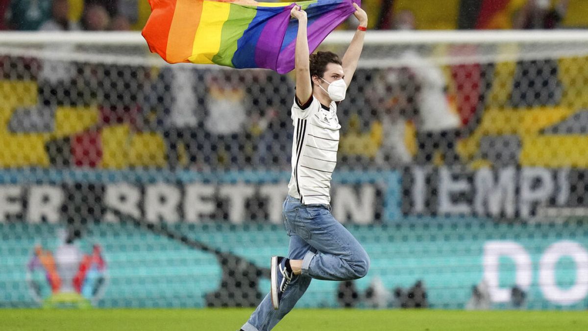 A fan with a LGBT pride flag runs on the pitch during the national anthems before the Euro 2020 soccer championship group F match between Germany and Hungary.