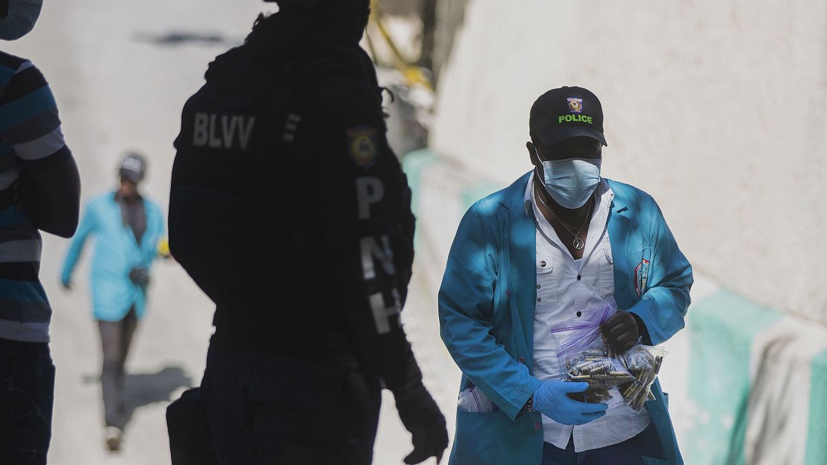 Um investigador da polícia do Haiti com um saco cheio de balas recolhidas no palácio presidencial
