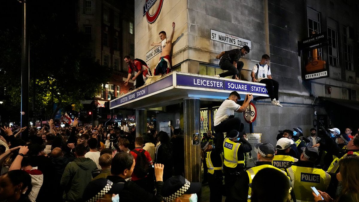 England fans react as they stand on the roof of Leicester Square underground station after England won their Euro 2020 semifinal match against Denmark on July 7, 2021.