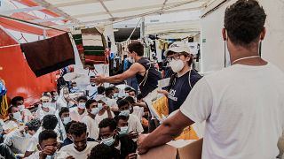 Staffers distribute food to migrants on the deck of the Ocean Viking rescue in the Mediterranean Sea