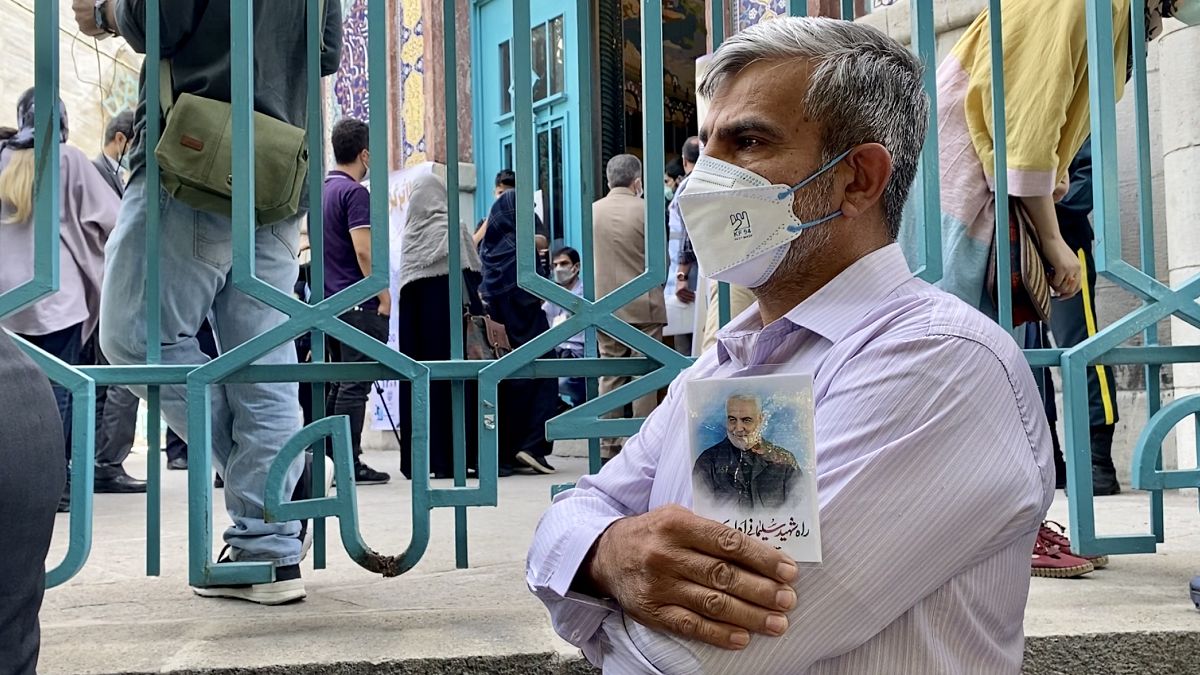 An Iranian voter outside a polling station in Tehran, June 18, 2021, holds up a picture of General Qassem Soleimani, who was killed in a US drone strike in January 2020.
