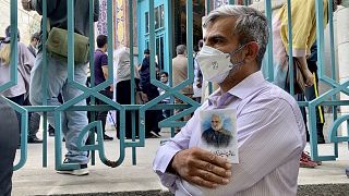 An Iranian voter outside a polling station in Tehran, June 18, 2021, holds up a picture of General Qassem Soleimani, who was killed in a US drone strike in January 2020.