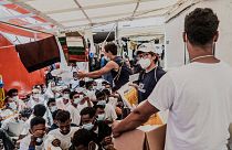 Staffers distribute food to migrants on the deck of the Ocean Viking rescue vessel.